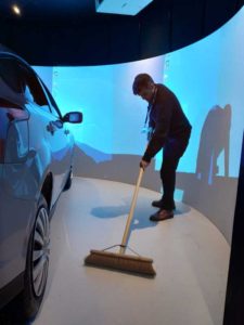 A man sweeping the floor next to the driving simulator
