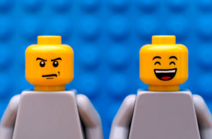 Two Lego figures stood side by side. One is smiling, the other is frowning.