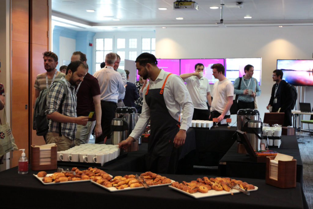 Coffee is being served to a delegate and three large sqaure plates of pastries in the forground